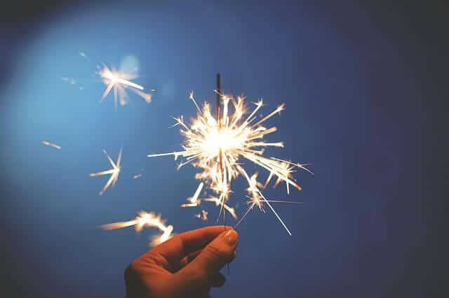 start your new year right blog post image of a sparkler and a someone holding it in their fingertips