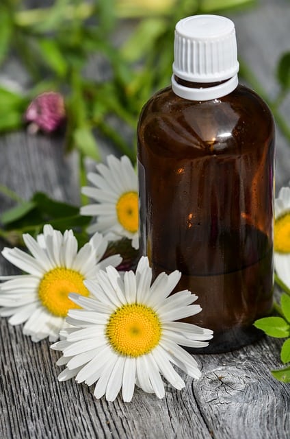 4 Holistic Ways to Reduce Stress in your life, dark bottle with daisies around it.