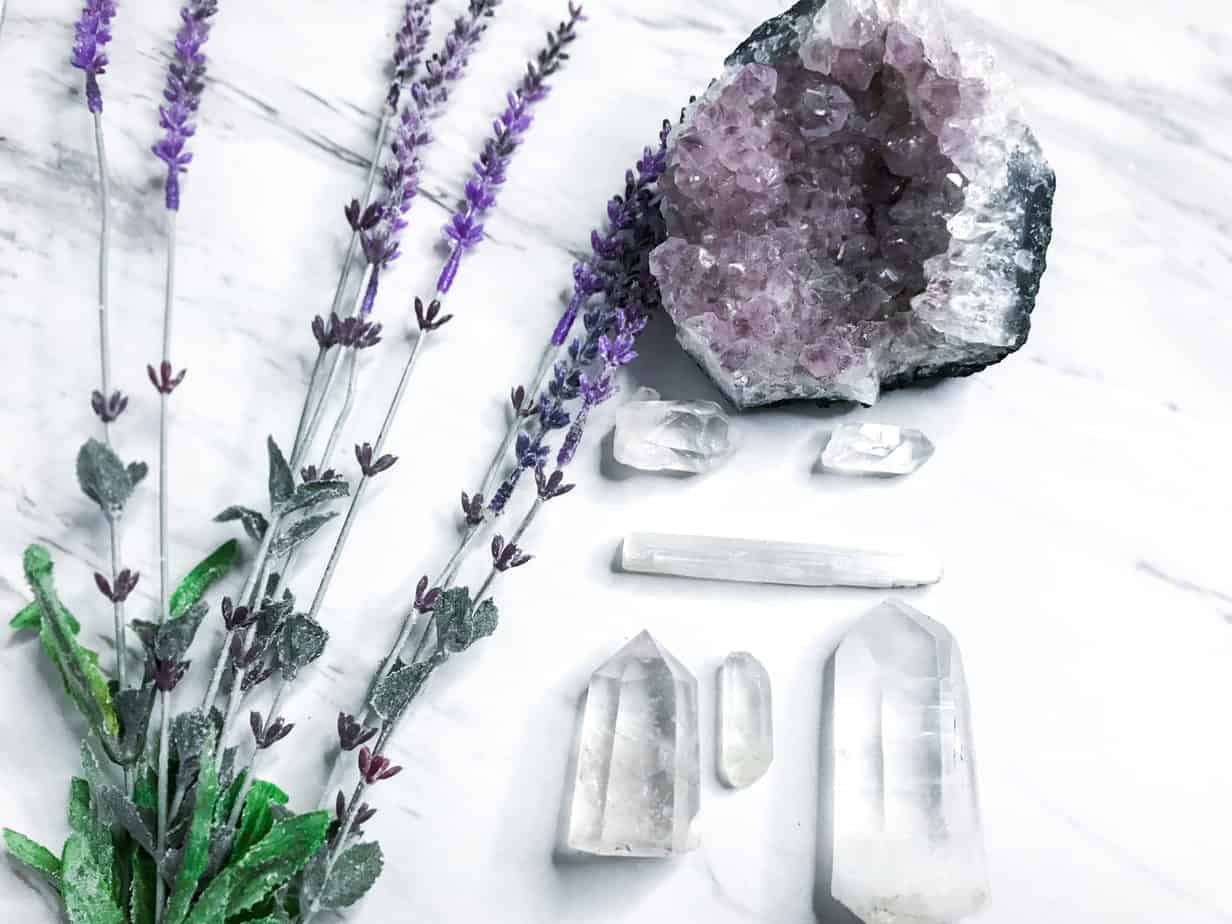 How to Use Crystals for Magickal & Mundane Witchy Life 7 3 of the best crystals for meditation, featuring an amethyst geode, clear quartz, lavender flowers