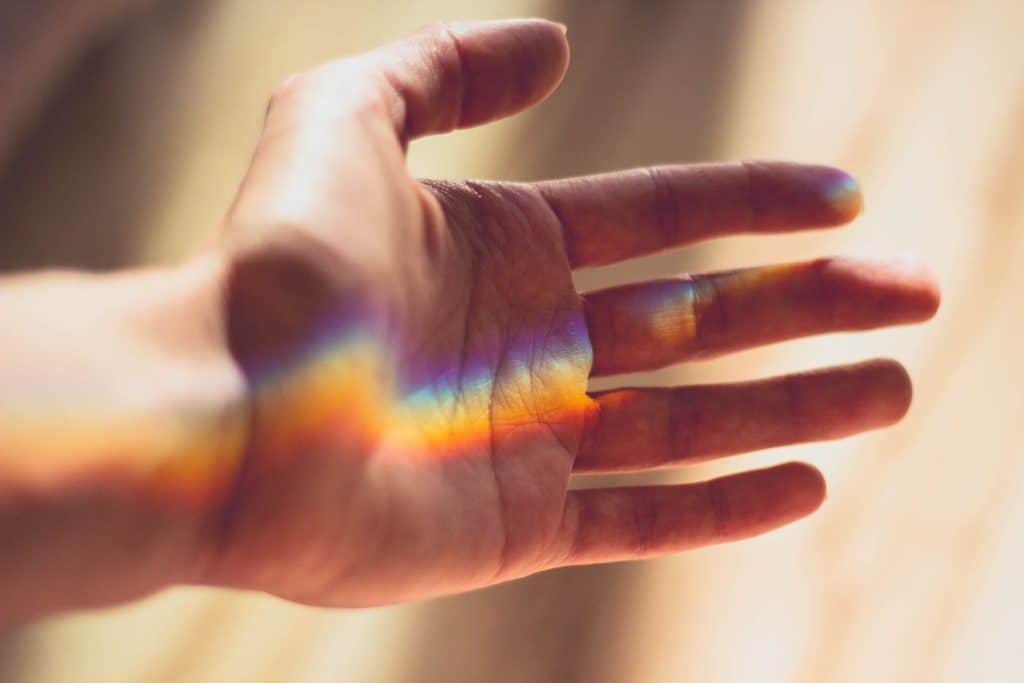 Hand with rainbow light. Tips for choosing a Reiki Master for your Reiki journey.