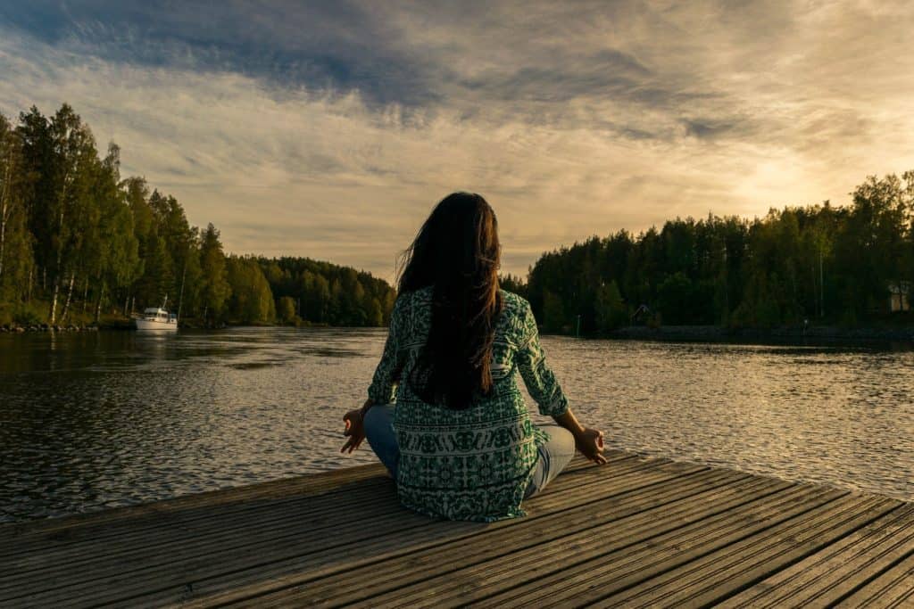 woman sitting on a dock in a relaxed pose - how to ground yourself