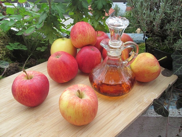 Apple cider vinegar surrounding by apples as an example of plant medicines found in your kitchen.