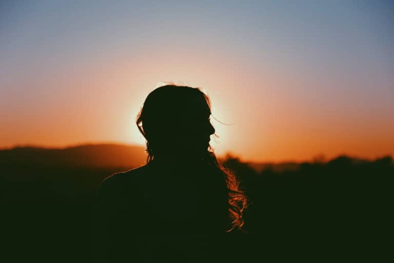 girl looking to the right at sunset. Just an outline of her.