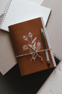 Brown journal with a flower design on the front and a pen, ready for journaling. 