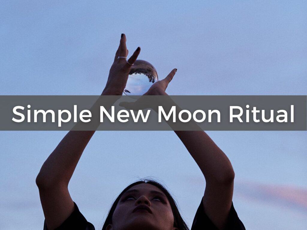 woman with hands raised toward sky with crystal ball to symbolize new moon ritual