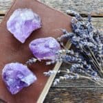 purple crystals on a brown book with sprigs of lavender nearby