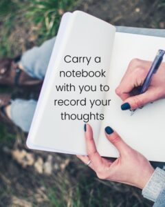 hands with polished nails and a notebook on her lap writing with a pen. Noted is carry a notebook with you to record your thoughts when creating your book of seasons.