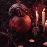 pumpkins with candles surrounding it with a dark background to depict Halloween/Samhain season