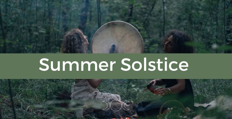 two women in a forest playing a large circular drum on summer solstice