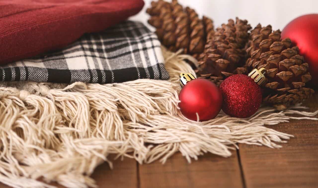 cozy blankets, pine cones and red Christmas ornaments 