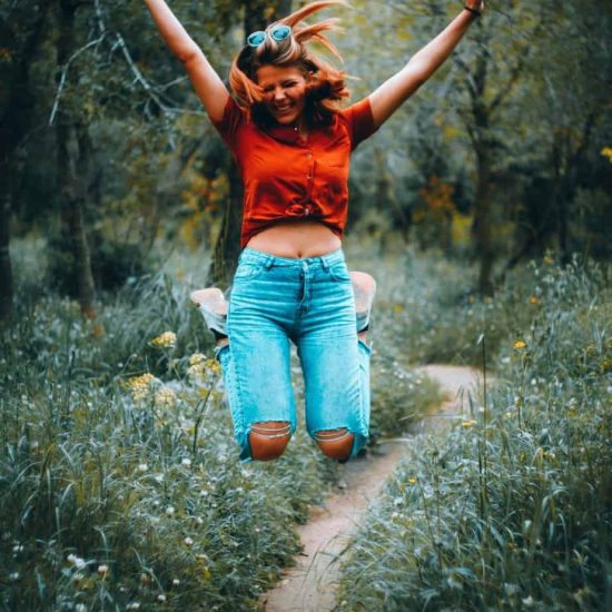 image is woman jumping high into the air with arms upraised and smiling.